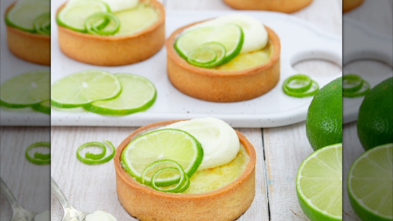 Mini key lime pie tarts topped with lime slices and whipped cream