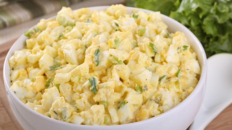 Bowl of egg salad with sliced croissant