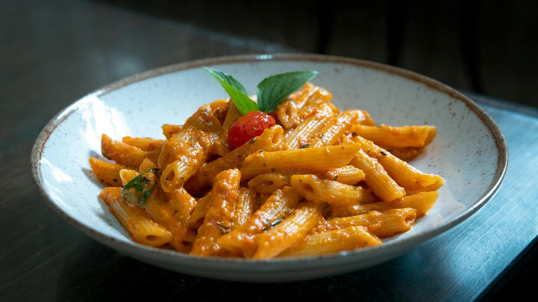 penne pasta in a blue bowl with creamy tomato sauce