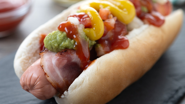 Upclose of a Sonoran style hot dog with salsa verde.