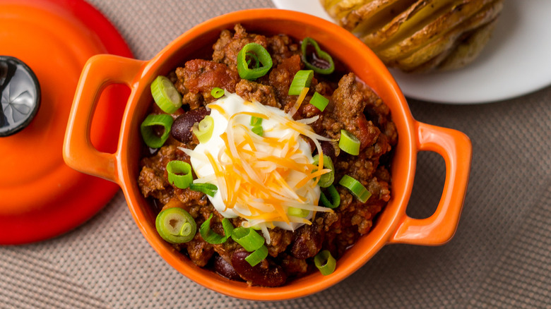 A pot of chili with sour cream and spring onion
