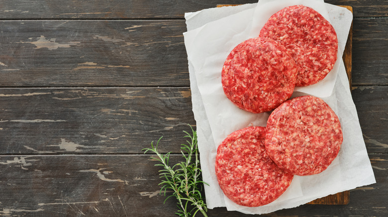 Beef patties on wooden board