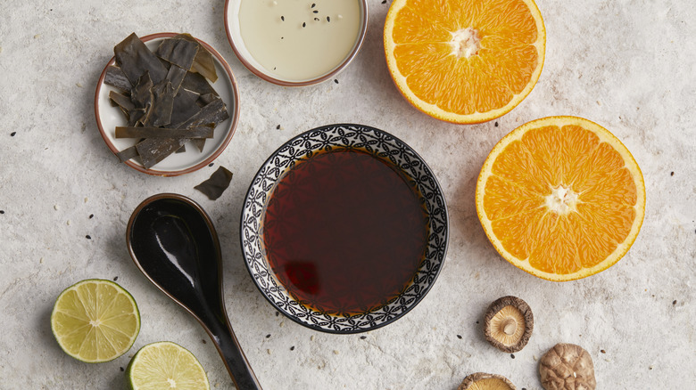 Ponzu sauce with add-ons like orange, lime, and dried mushrooms and seaweed