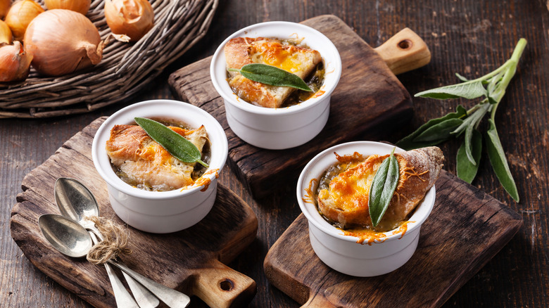 Crocks of French onion soup on cutting boards garnished with herbs