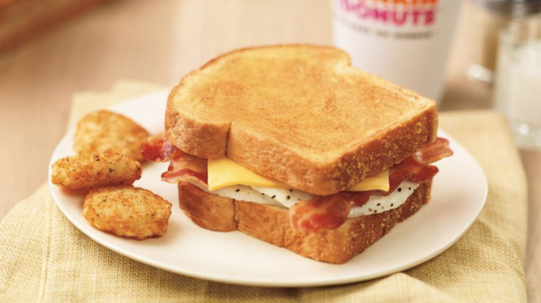 A Dunkin' Big N' Toasted on a plate with some hashbrowns