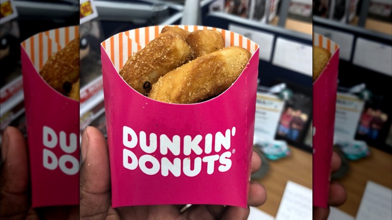 A close up of someone's hand holding a pack of Dunkin' Donut Fries