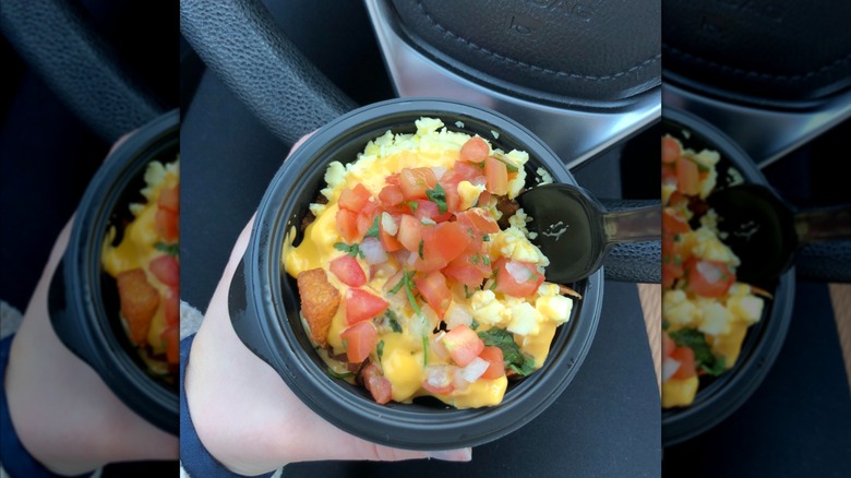 A close up of the Taco Bell Mini Skillet Bowl, as someone eats it in their car