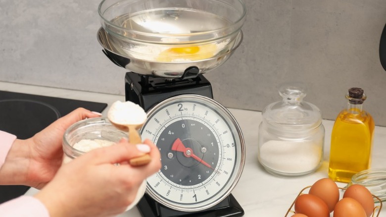 A cook measuring flour using a retro kitchen scale