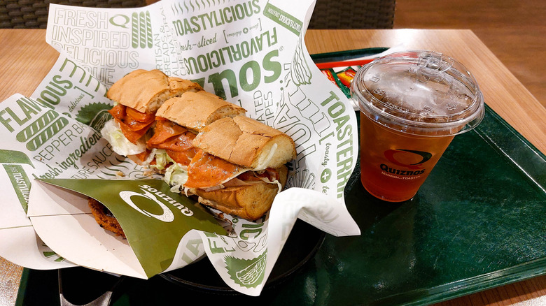 A Quiznos sub on a tray with a drink