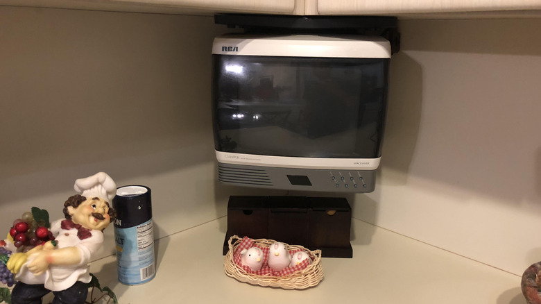 A TV set sitting on a ktichen counter next to some '90s kitchen decor