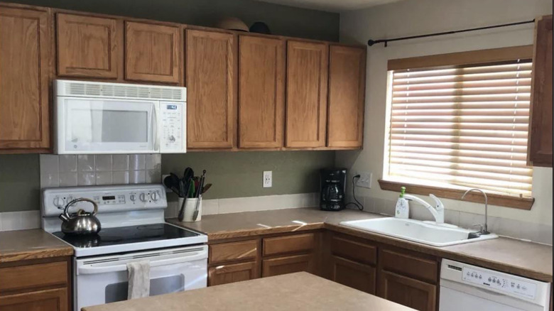 A '90s kitchen with light brown cupboards andn drawers