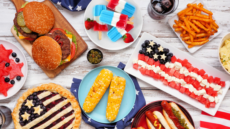 A Fourth of July-themed spread includes burgers, corn on the cob, and red, white, and blue foods.