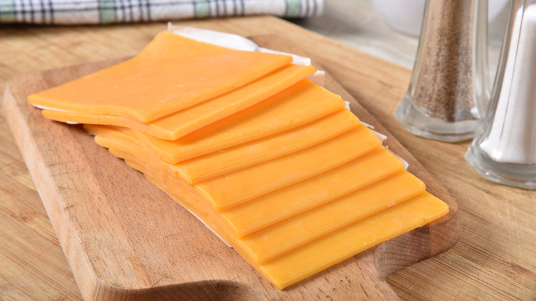 Slices of orange cheese are arranged on a cutting board.