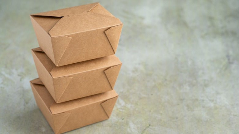 Brown, restaurant-style takeout boxes are stacked on top of one another.