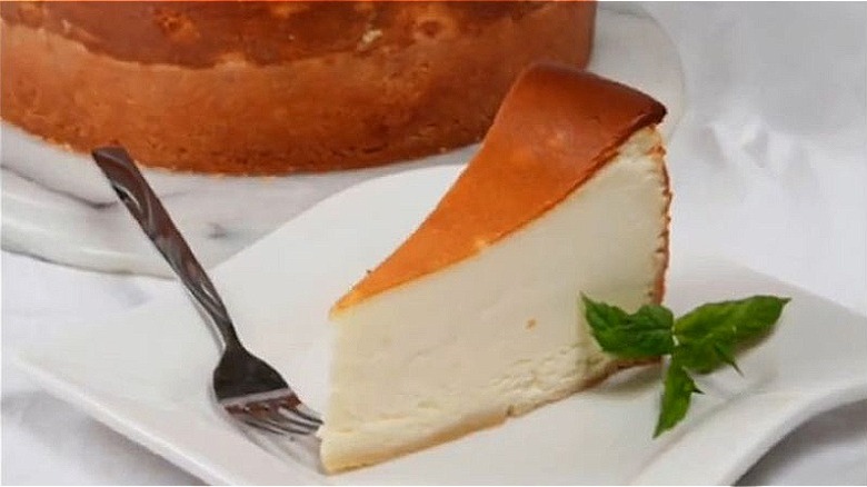 New York Style cheesecake slice on square white plate with fork.