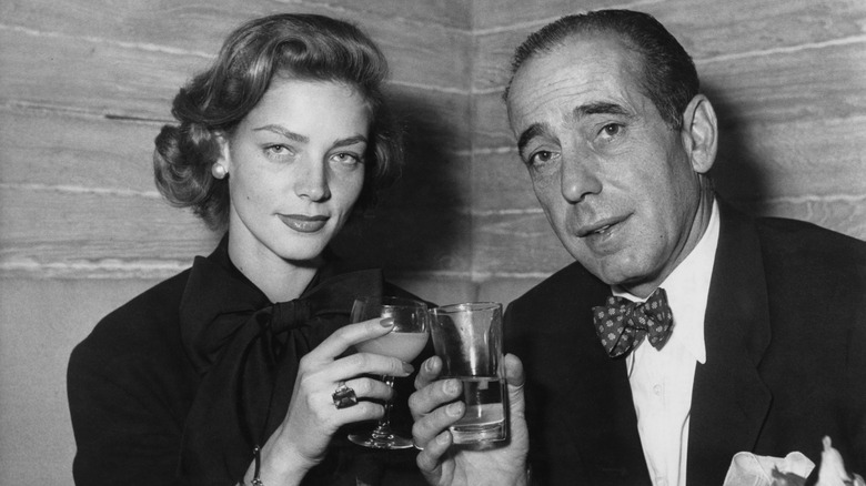 Black and white of Humphrey Bogart having a drink with Lauren Bacall