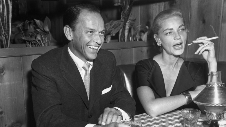 Frank Sinatra and Lauren Bacall sit together at a restaurant.