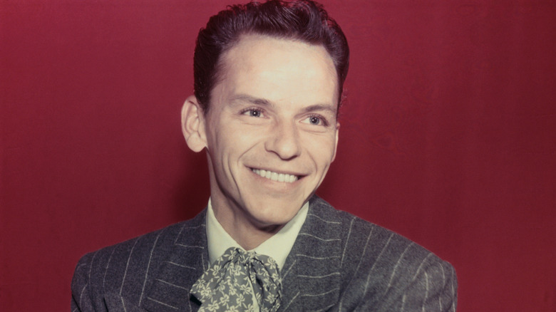 Young Frank Sinatra smiles in front of a red background