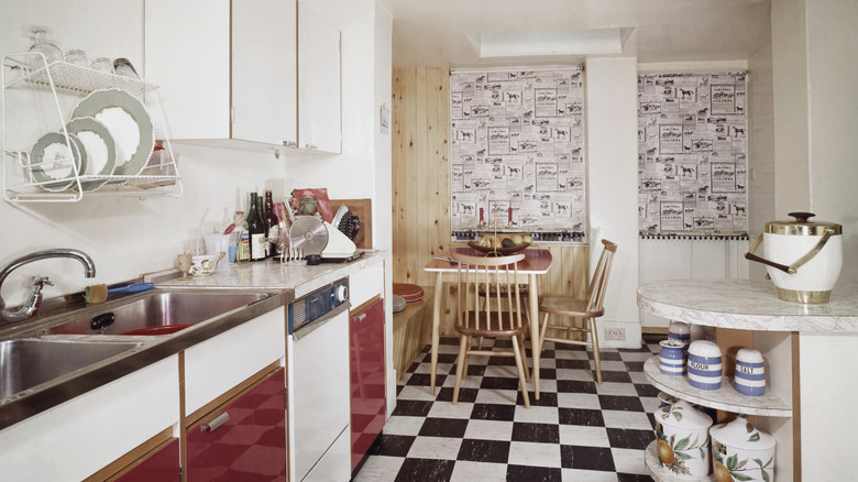 Retro kitchen from the 1950s with red cabinets, checkered floors, and assorted furniture and kitchen essentials