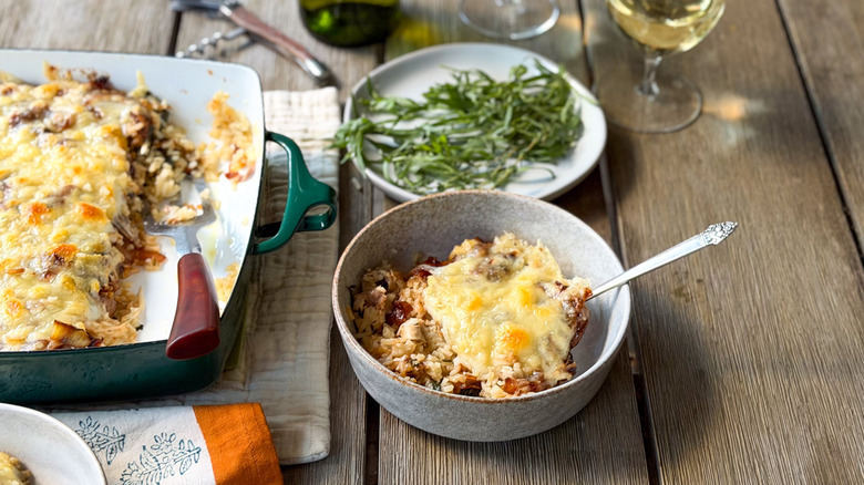 French onion chicken and rice casserole in serving dish and bowl with fresh tarragon