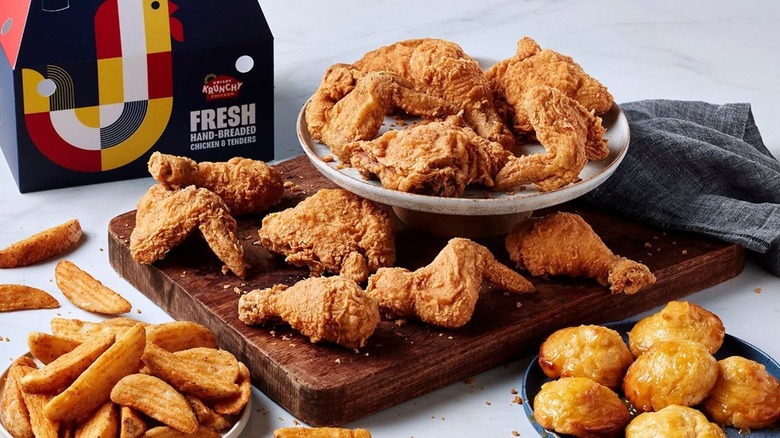 a box of Krispy Krunchy Chicken among a plate of fried chicken, biscuits, and potato wedges