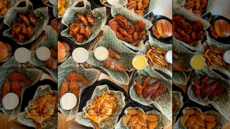 to-go containers of differently flavored Wingstop wings and sides with ramekins of dressing