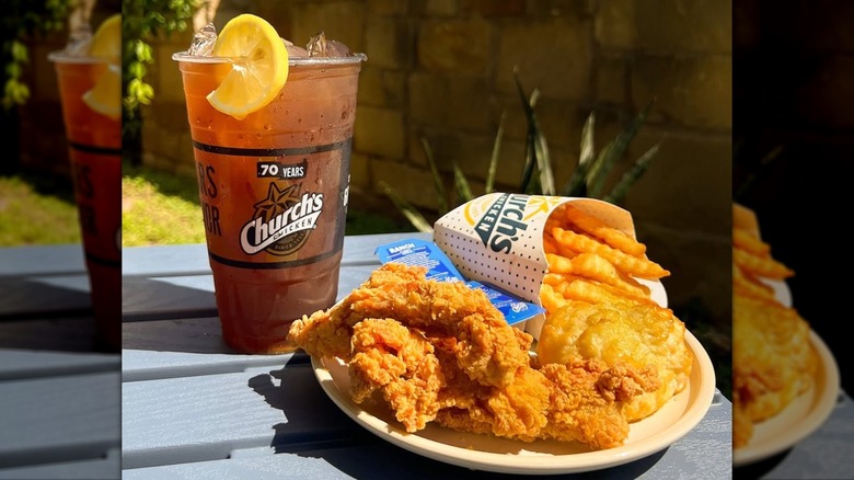 Church's Chicken meal on picnic table in the sun with iced tea cup behind it