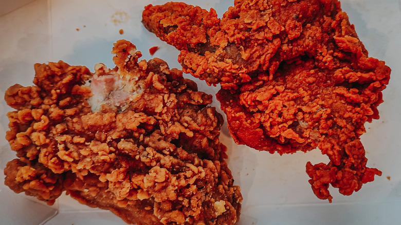 Two pieces of fried chicken with different color fried skin due to different breading