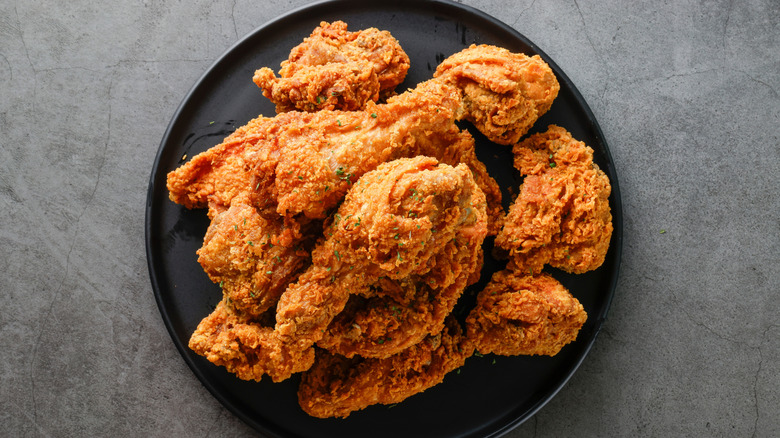 Fried chicken sprinkled with herbs on a black plate