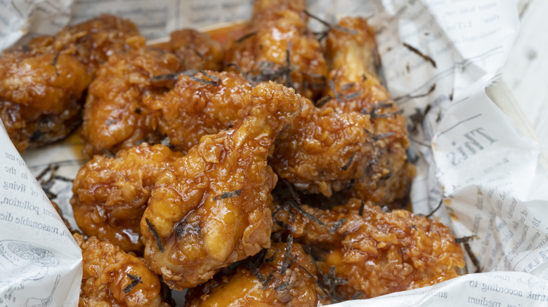 A basket of deep-fried chicken wings covered in a spicy sauce.