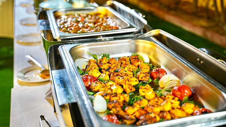 A restaurant buffet with a chicken and vegetable dish in the foreground.
