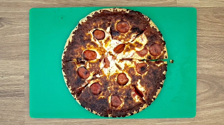 Baked pepperoni pizza on a green cutting board