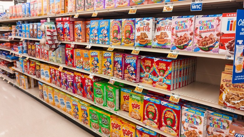 Rows of different kinds of popular sugary cereals lining an aisle in an American grocery store.