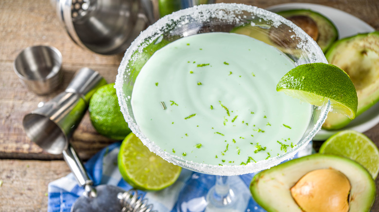 Creamy avocado margarita in a glass with limes