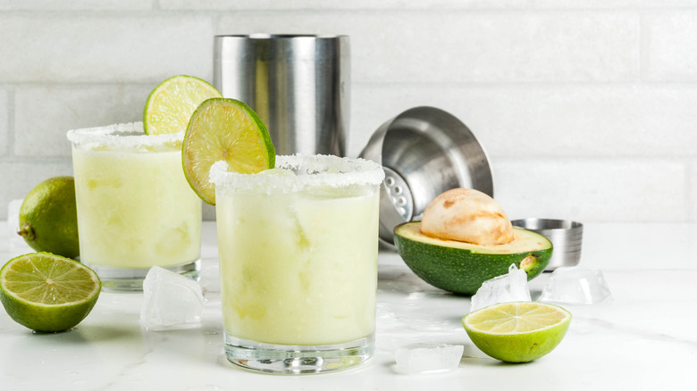Creamy margarita in two glasses with limes and avocados on the side