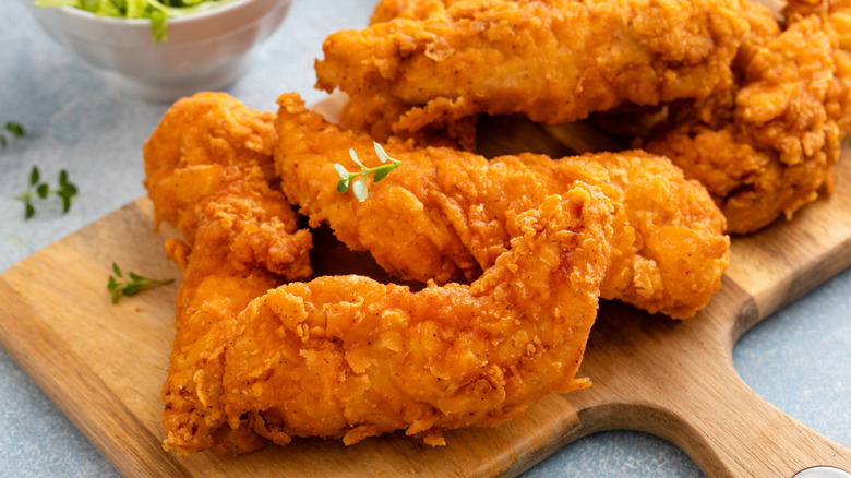 Chicken tenders on a wooden board.