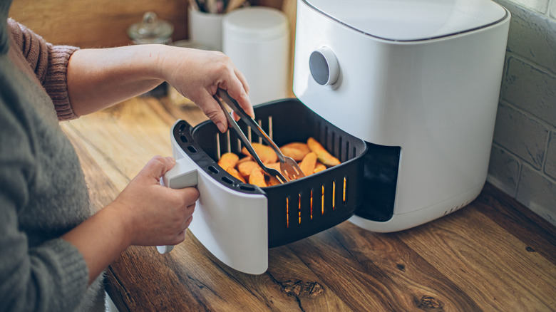 Woman using air fryer in kitchen