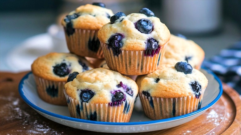 Blueberry muffins piled onto a white, blue-trimmed plate