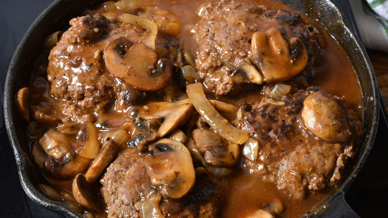 Salisbury steak with mushrooms in a cast iron skillet.