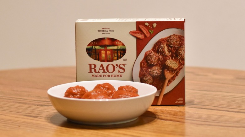 A box of Rao's meatballs and sauce next to a white bowl of prepared meatballs