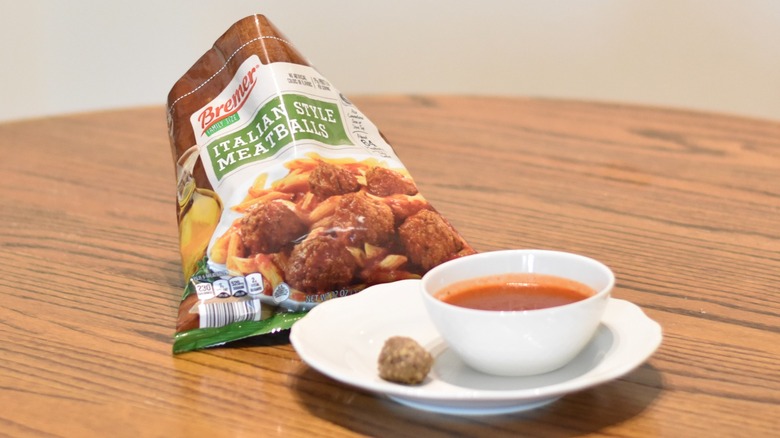 A bag of Bremer Italian meatballs with a meatball and marinara on a white plate