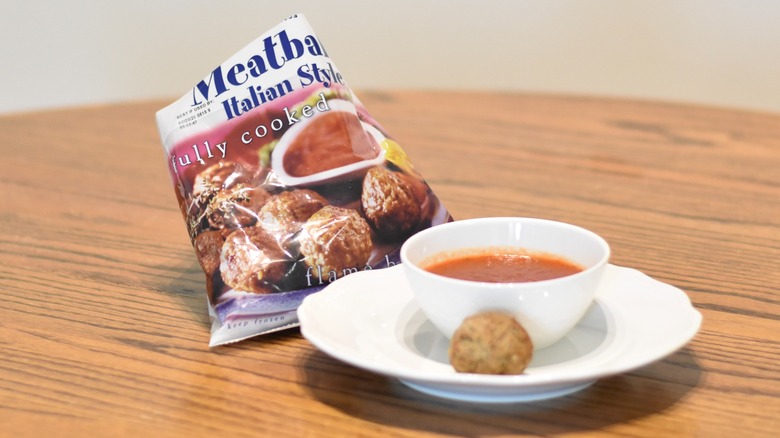 A bag of Trader Joe's meatballs next to a meatball and marinara on a white plate