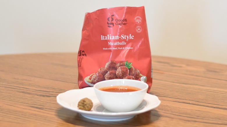 A bag of Good & Gather meatballs next to a meatball and marinara on a white plate