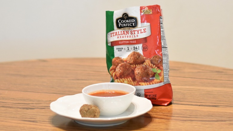 A bag of Cooked Perfect meatballs next to a meatball and marinara on a white plate