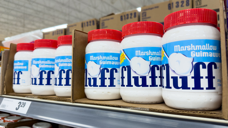 Containers of marshmallow fluff sitting on a store shelf in a grocery store.