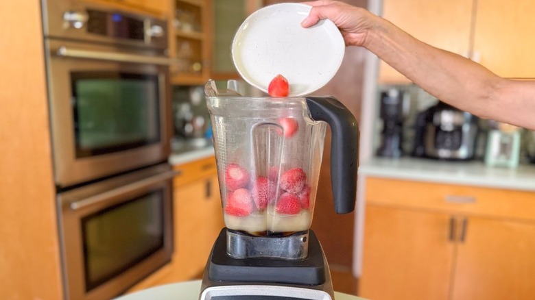 Adding frozen strawberries to blender pitcher