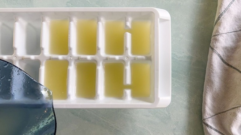 Pouring fresh lime juice into an ice cube tray