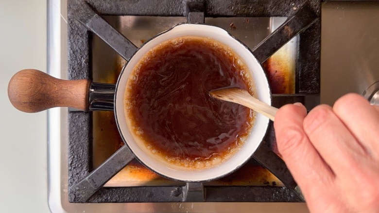Stirring turbinado sugar syrup in small saucepan with wooden spoon