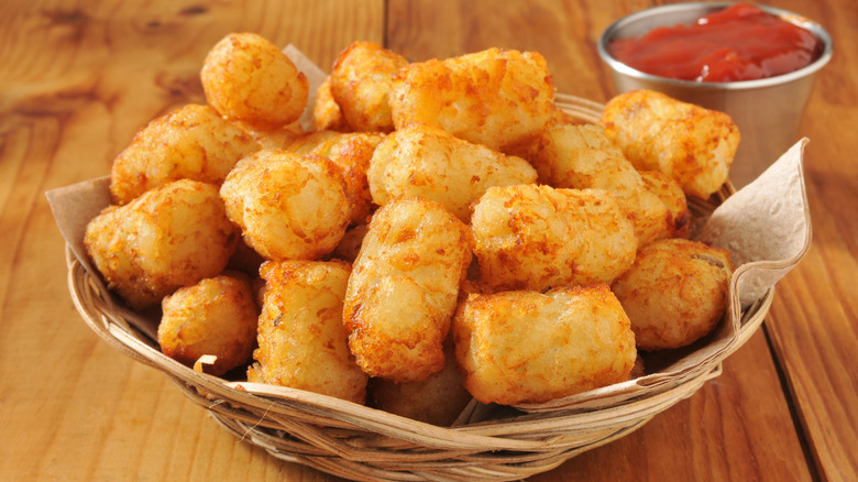 Crispy tater tots in a basket on a table.