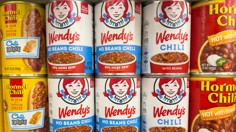 Canned chili brands on a grocery store shelf.